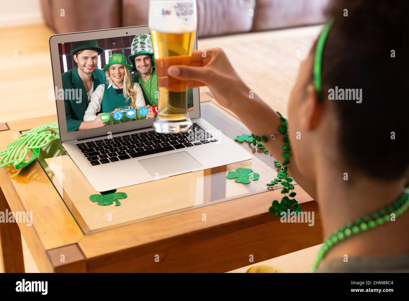 Femme afro-américaine tenant un verre à bière avec un appel vidéo sur ordinateur portable à la maison Banque D'Images