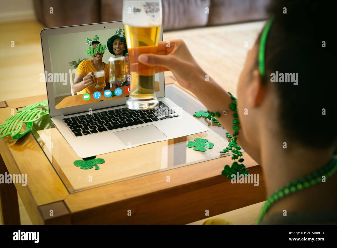 Femme afro-américaine tenant un verre à bière avec un appel vidéo sur ordinateur portable à la maison Banque D'Images