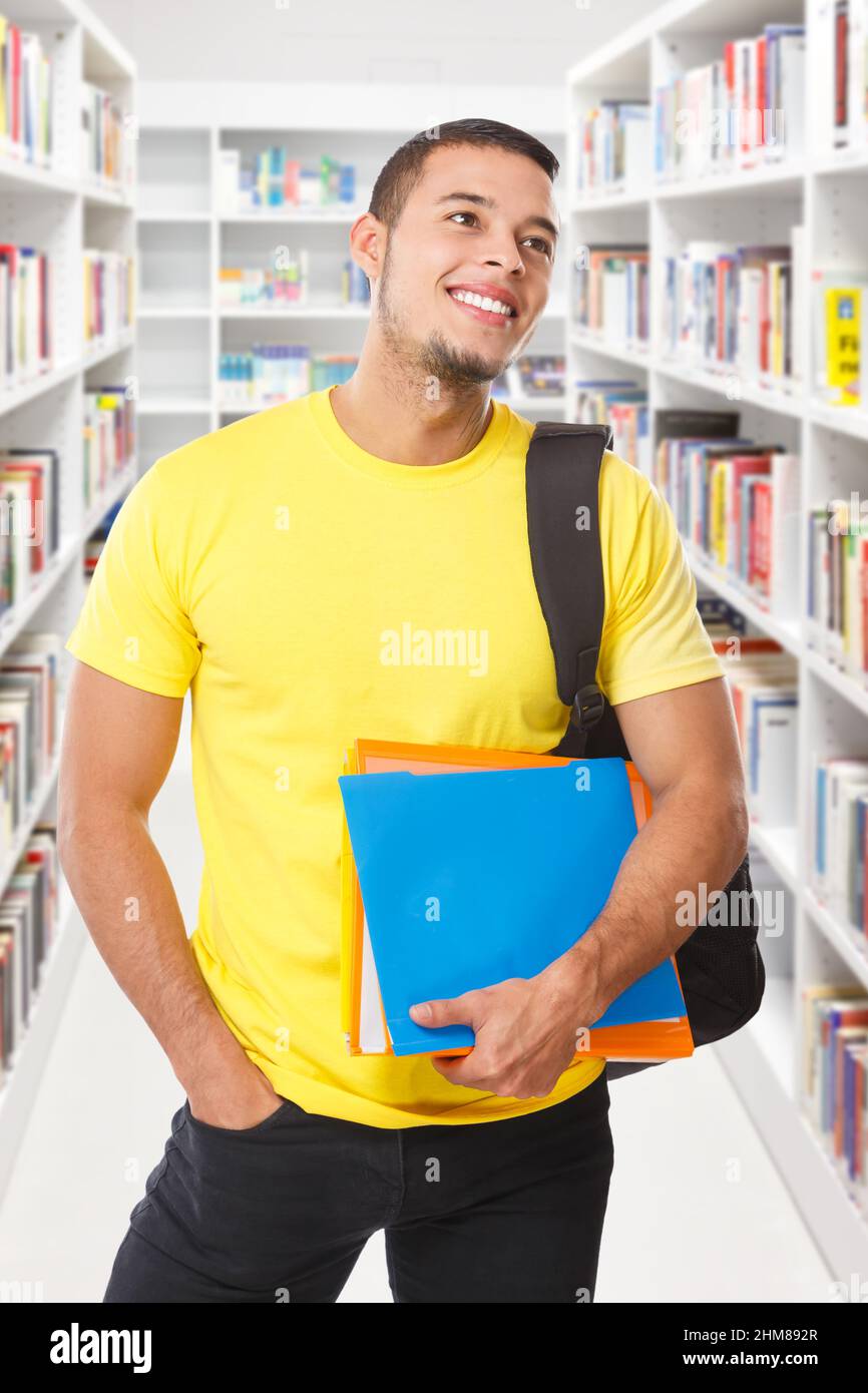 Étudiant à la recherche regarder bibliothèque livres format portrait sourire heureux jeune homme personnes livre Banque D'Images
