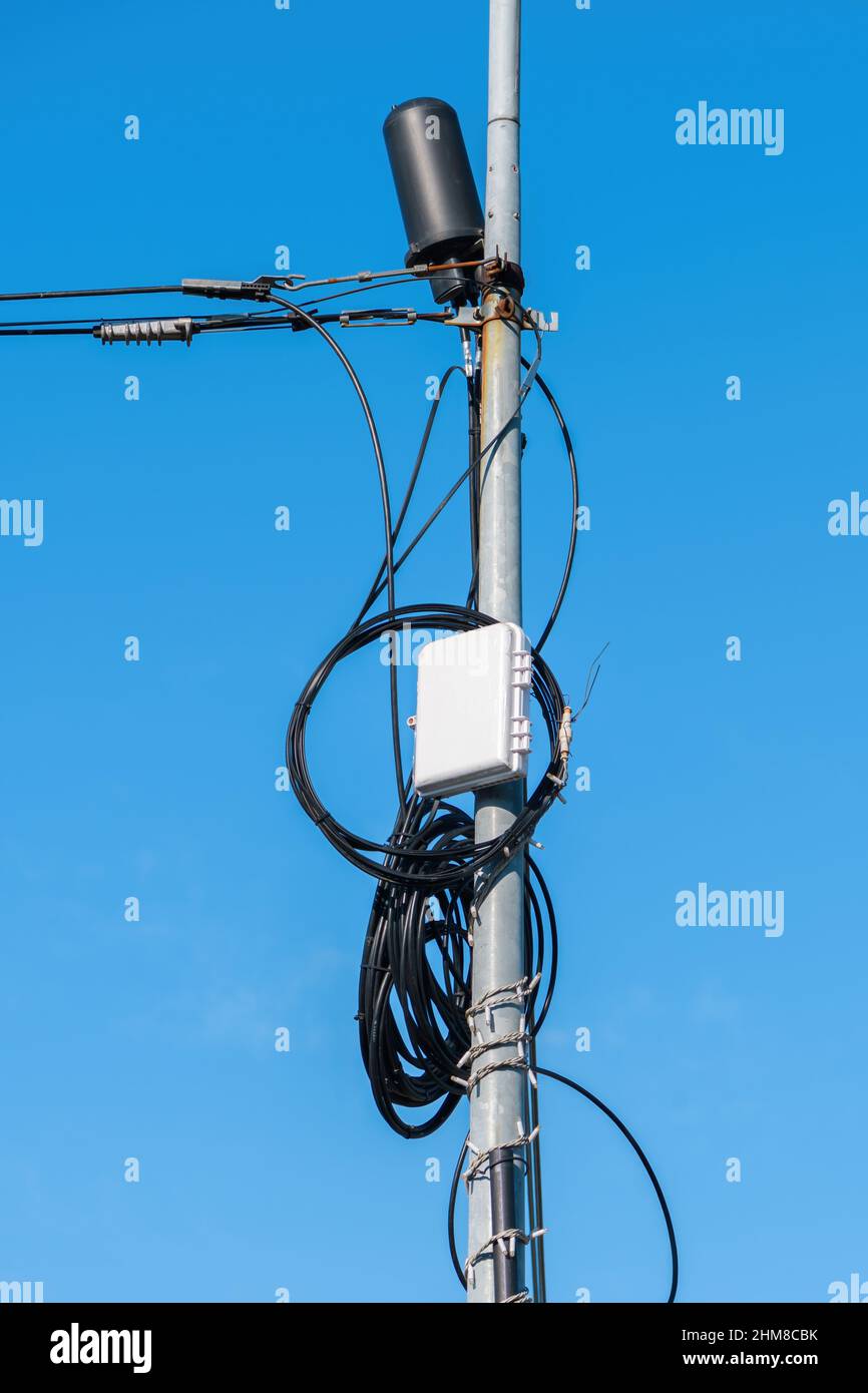 Boîtier de mise à la terre de la télévision par câble monté sur le poteau de l'utilitaire contre le ciel bleu Banque D'Images