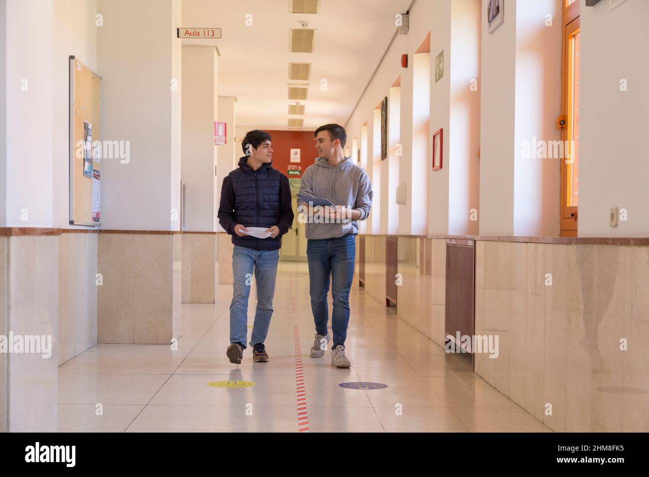 deux amis étudiants de l'université marchant dans un couloir parlant Banque D'Images