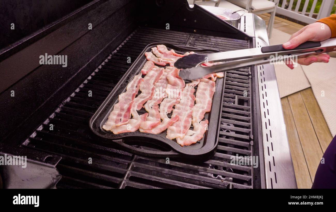 Cuisson de tranches de bacon sur un barbecue à gaz extérieur. Banque D'Images
