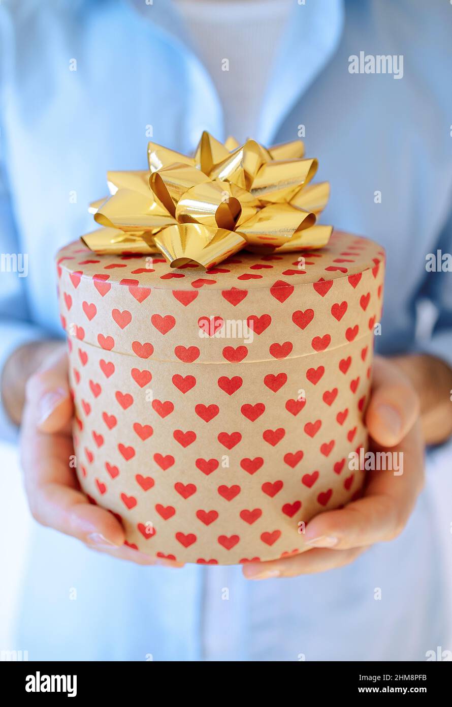 Main de l'homme tenant une boîte cadeau avec des coeurs présents avec un  noeud doré.Livraison express, solde de Noël.Achats en ligne.Saint Valentin  Photo Stock - Alamy