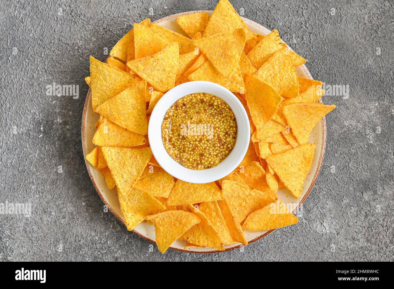 Chips de maïs avec moutarde dans une assiette sur fond gris. Vue de dessus espace de copie. Banque D'Images