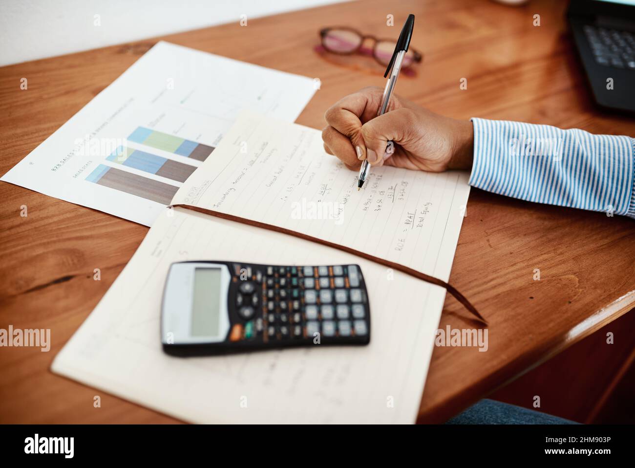 Les comptes vivent leur vie dans l'équilibre. Photo rognée d'une femme d'affaires qui écrit des données financières dans un bloc-notes à son bureau. Banque D'Images
