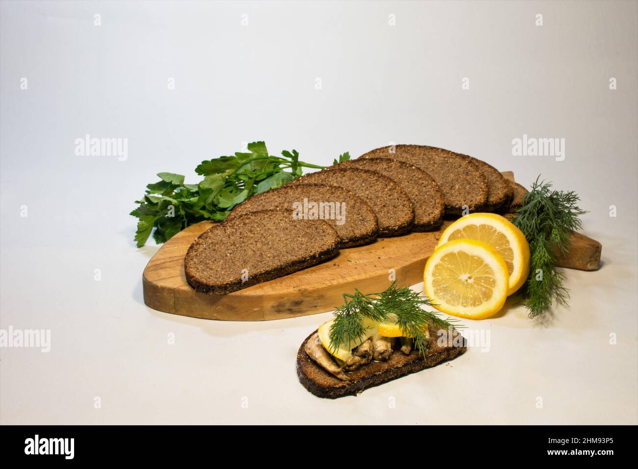 Tranches de pain ​​rye sur une planche de bois, aneth, tranches de citron et sandwich avec des crawrats fumés dans l'huile. Banque D'Images