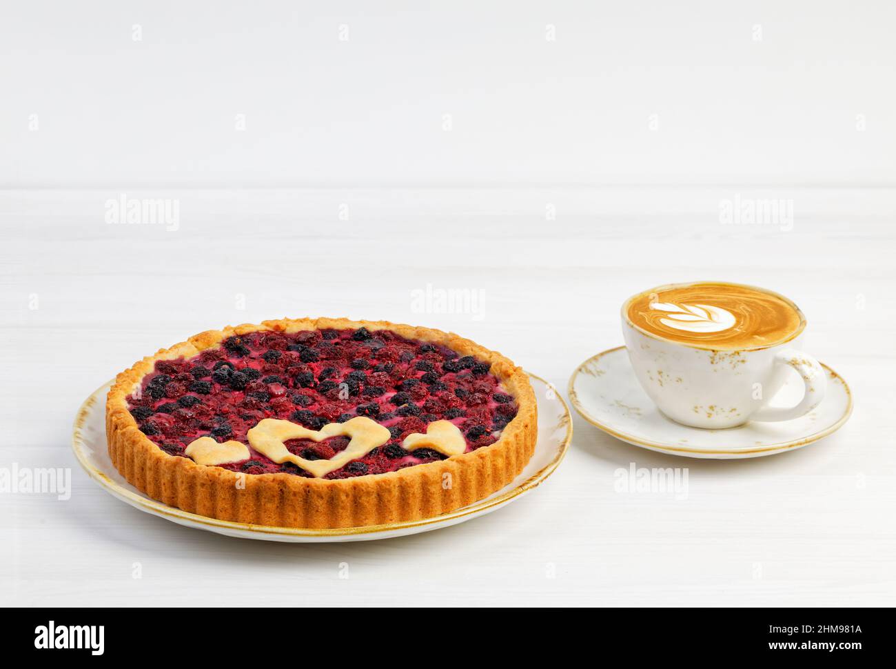 Tarte ouverte maison aux framboises rouges et noires et une tasse de cappuccino au café sur une table en bois blanc. CopySpace. Banque D'Images Tarte ouverte maison aux framboises rouges et noires et une tasse de cappuccino au café sur une table en bois blanc. CopySpace. Banque D'Images