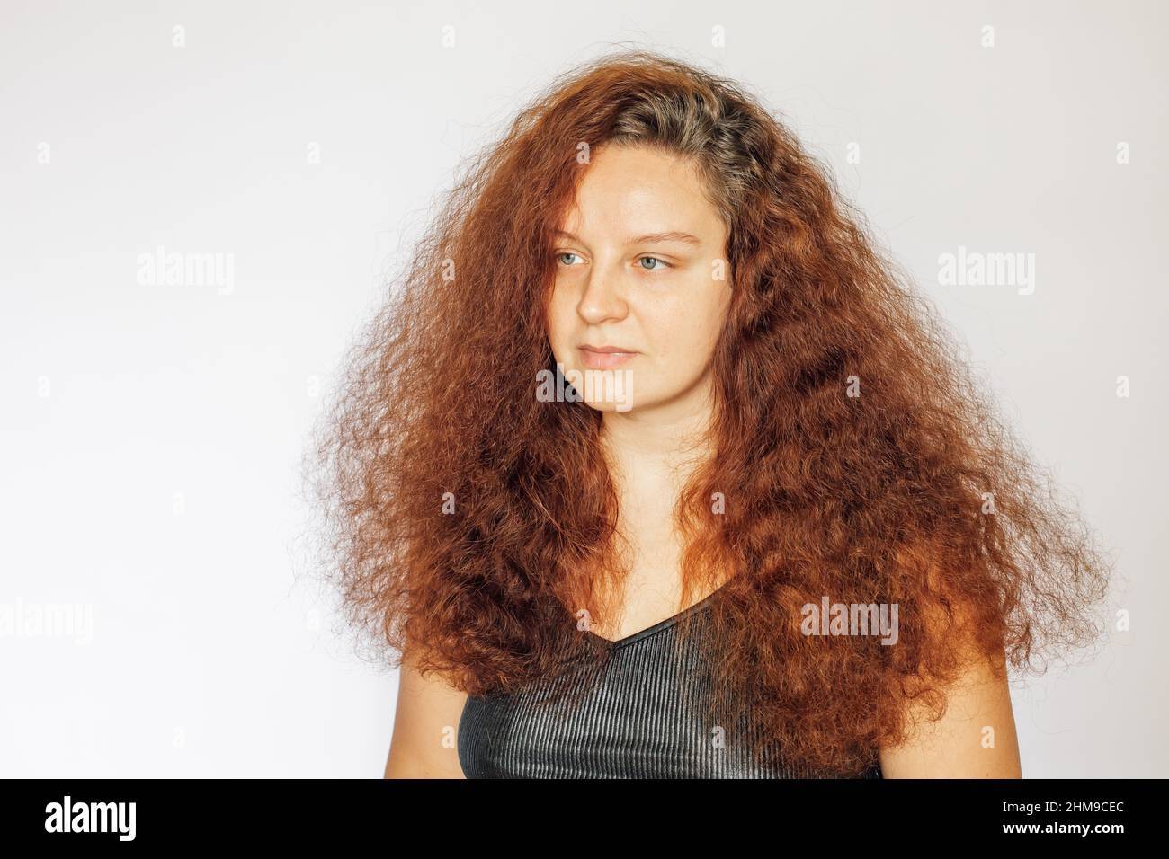 Portrait de la femme caucasienne avec des cheveux bouclés luxuriants de couleur rouge, peau propre du visage sans maquillage et yeux regardant loin sur fond blanc. Moi-même Banque D'Images