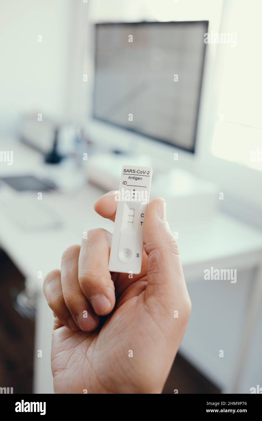 gros plan d'un jeune homme dans le bureau ayant dans sa main un dispositif de test de diagnostic d'antigène covid-19 avec un résultat positif Banque D'Images