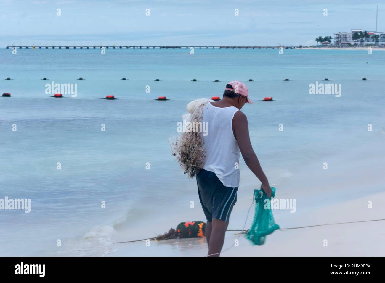 Vue d'un pêcheur marchant au bord de la mer avec un filet de pêche au-dessus de son épaule, à Playa del Carmen, au Mexique Banque D'Images
