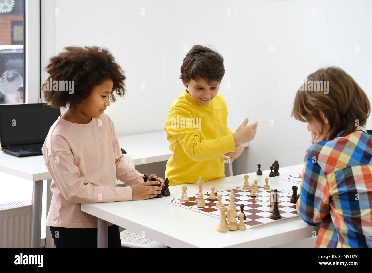 Groupe diversifié d'enfants jouant aux échecs. Enfants intelligents multiethniques concentrés avec jeu de société s'amuser à l'école. Fille afro-américaine et Banque D'Images