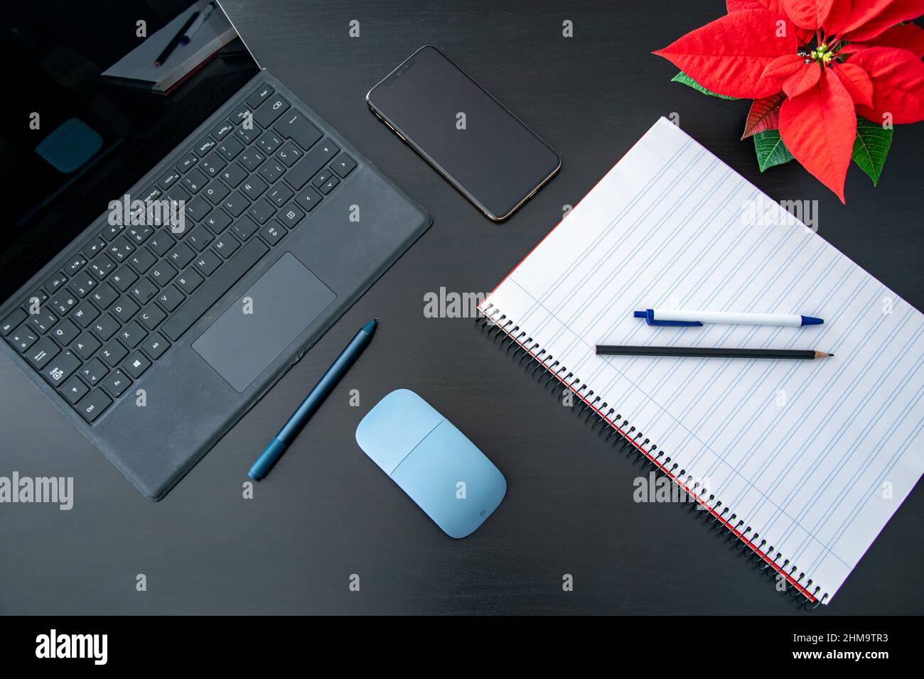 Image d'une tablette pour ordinateur portable, bloc-notes avec un téléphone portable sur une table noire à côté d'une fleur rouge prêt à étudier ou à travailler à la maison Banque D'Images