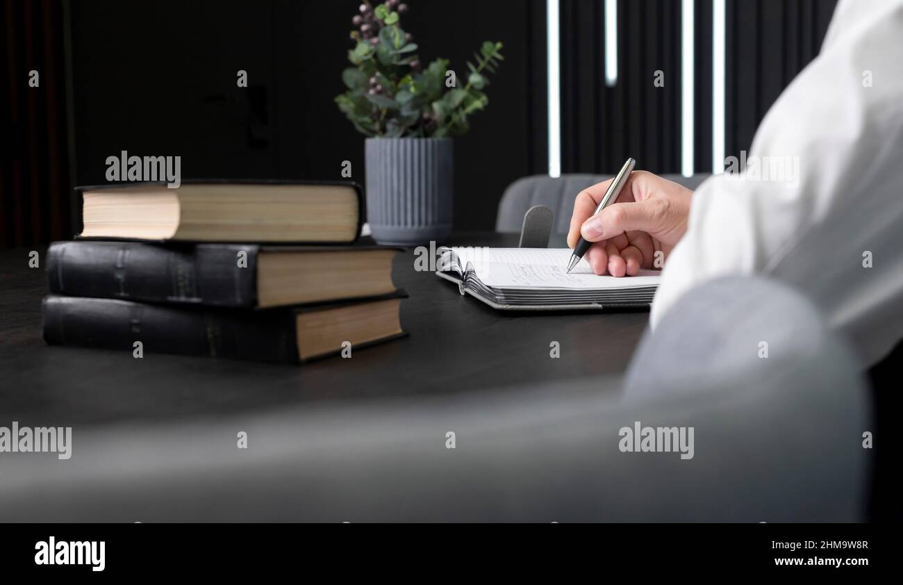 Homme mains prendre des notes dans le carnet. Homme d'affaires assis à table avec des livres ou des codes et de l'ordre du jour écrit, l'information pour l'éducation ou le travail. Photo de haute qualité Banque D'Images
