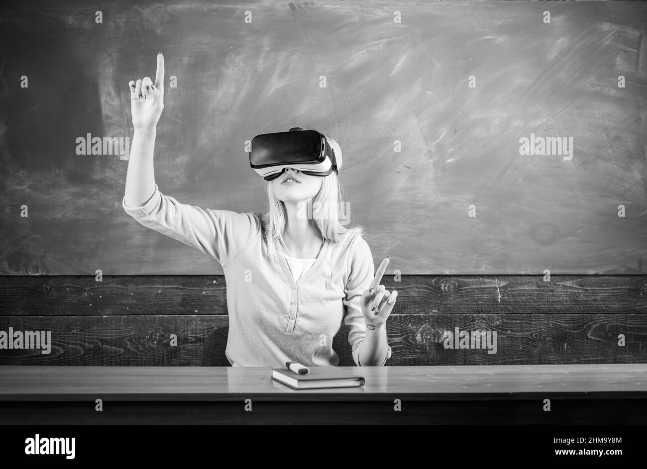 Portrait d'un élève excité, les bras sont équipés d'un casque vr. Étudiant prêt à vivre une expérience VR. Femme assise au bureau avec ordinateur portable et mise sur virtuel Banque D'Images