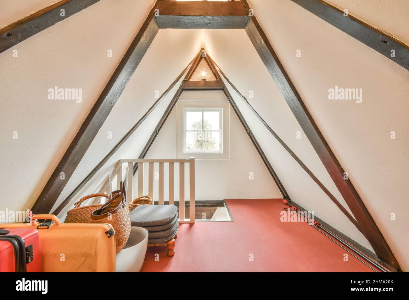 Valises près des étagères avec divers récipients et sac placés dans un grenier clair avec plancher rouge et fenêtre dans l'appartement Banque D'Images