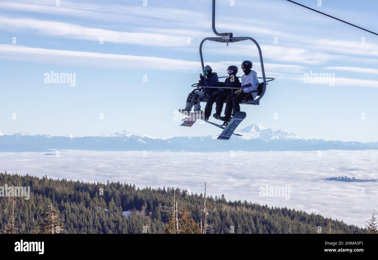Personnes sur un télésiège à la station de ski de Grouse Mountain avec mnt Baker en arrière-plan Banque D'Images