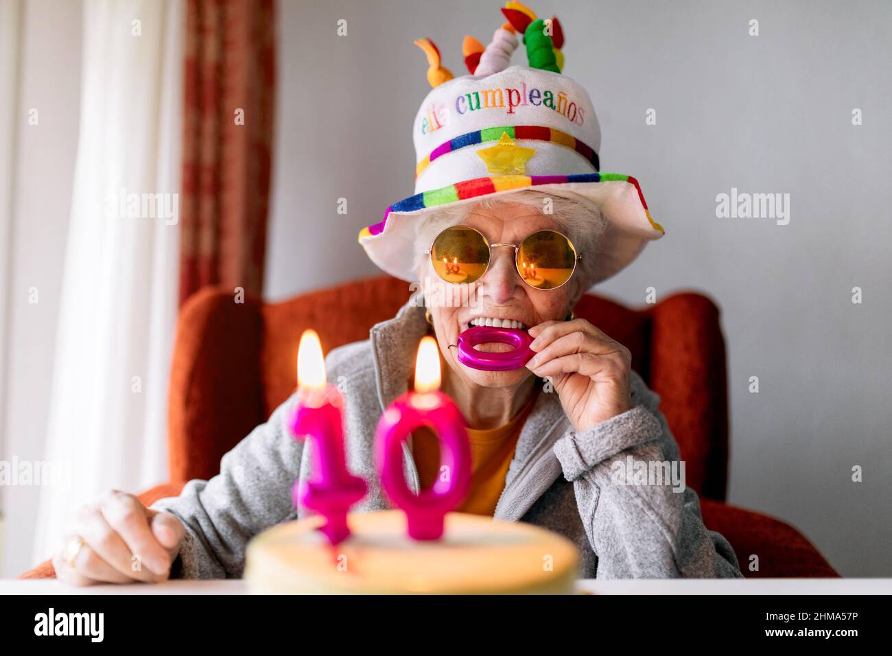 Gaie femme âgée en lunettes de soleil et chapeau drôle piquant bougie tout  en célébrant 100 anniversaire avec gâteau d'anniversaire et regarder  l'appareil photo Photo Stock - Alamy