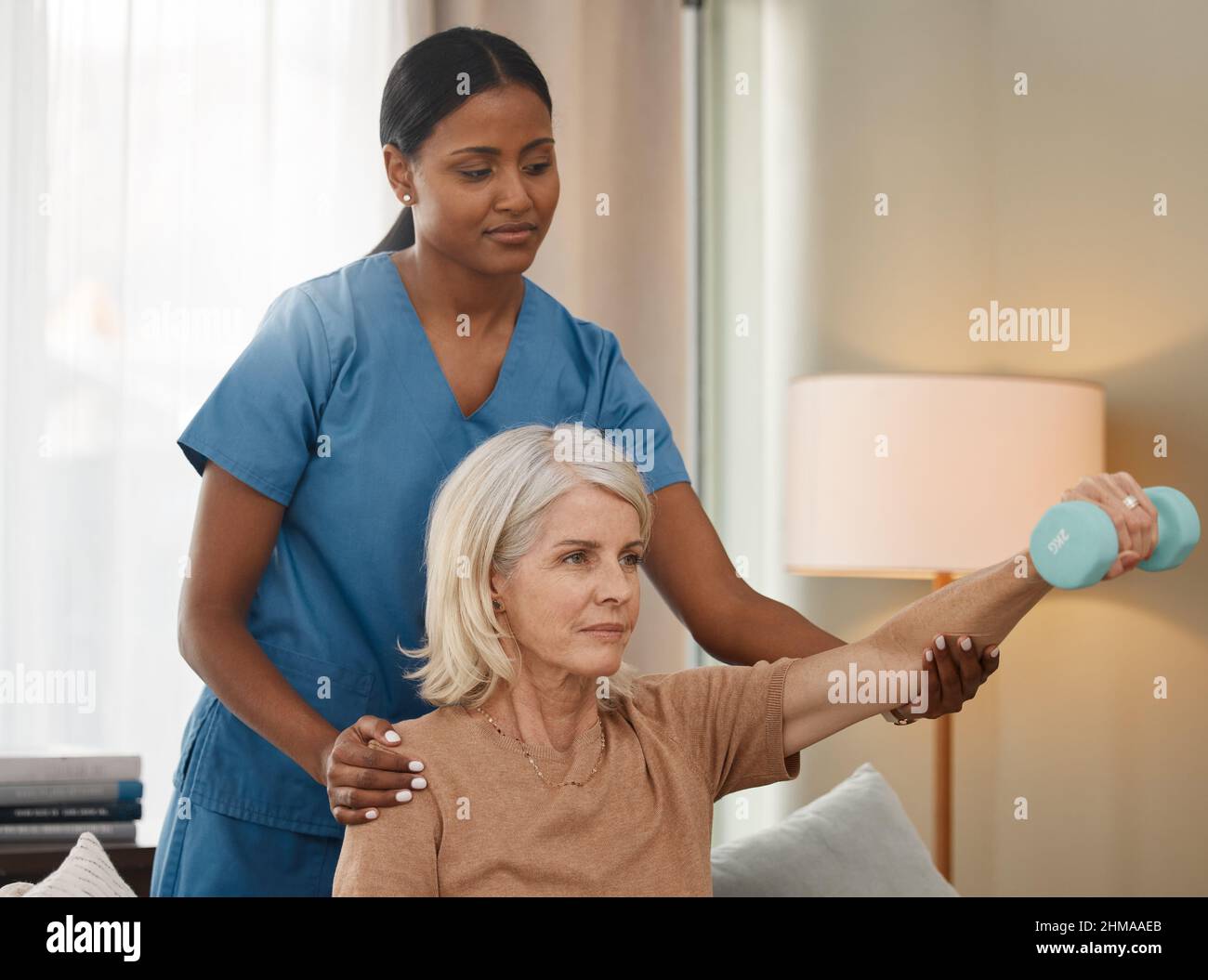 Vivre une vie meilleure avec chaque ascenseur. Prise de vue d'une femme âgée utilisant des haltères pendant un examen avec son médecin à la maison. Banque D'Images