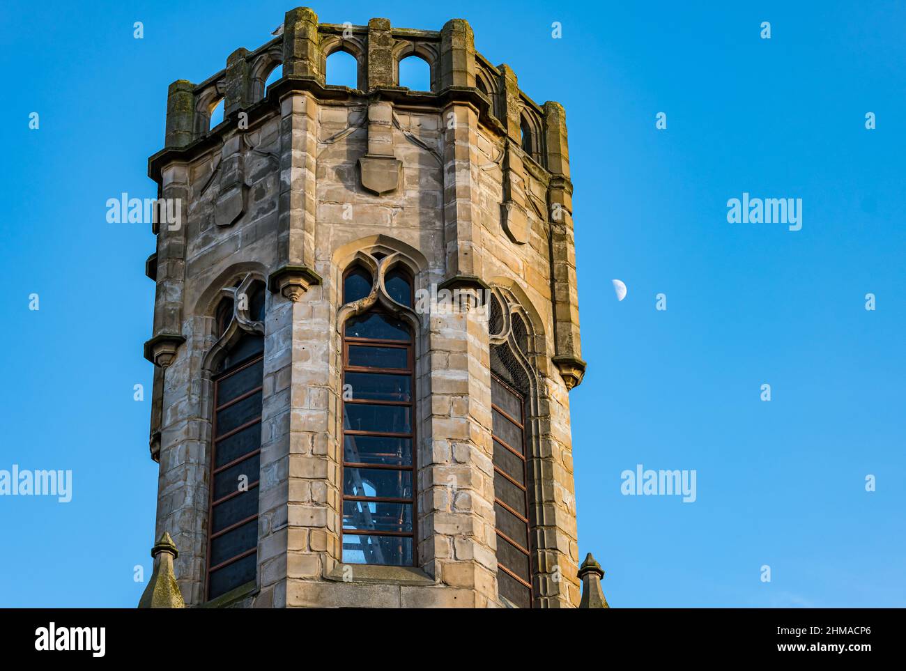 Tour d'église hexagonale avec une demi-lune visible dans le ciel bleu clair, Leith, Edinburgh, Écosse, Royaume-Uni Banque D'Images