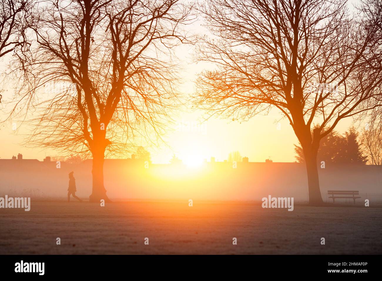 Les gens marchent dans un parc couvert de brume et de gel à Ilford, dans l'est de Londres, au lever du soleil. Banque D'Images