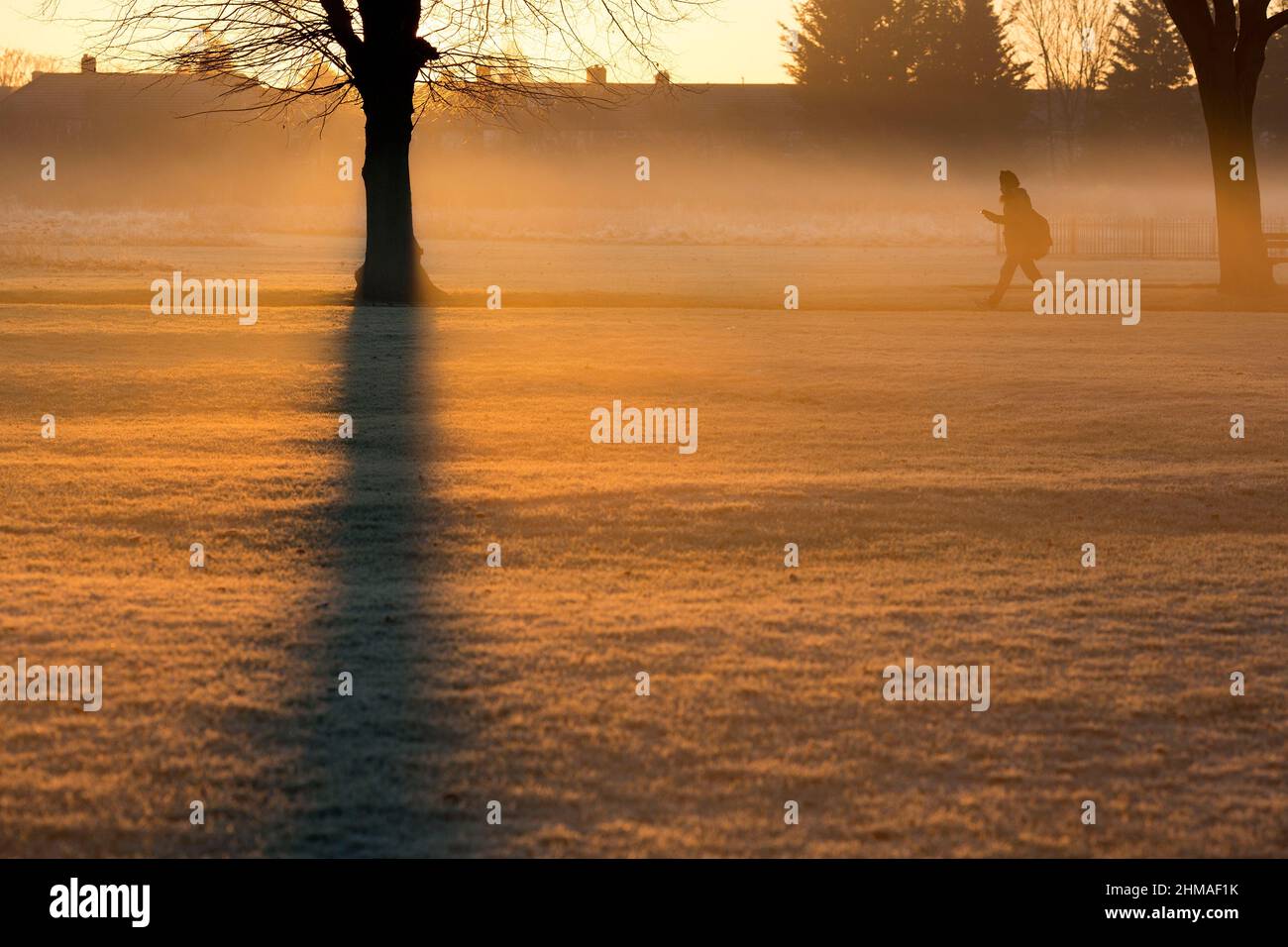 Les gens marchent dans un parc couvert de brume et de gel à Ilford, dans l'est de Londres, au lever du soleil. Banque D'Images