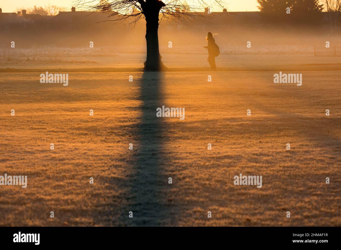 Les gens marchent dans un parc couvert de brume et de gel à Ilford, dans l'est de Londres, au lever du soleil. Banque D'Images
