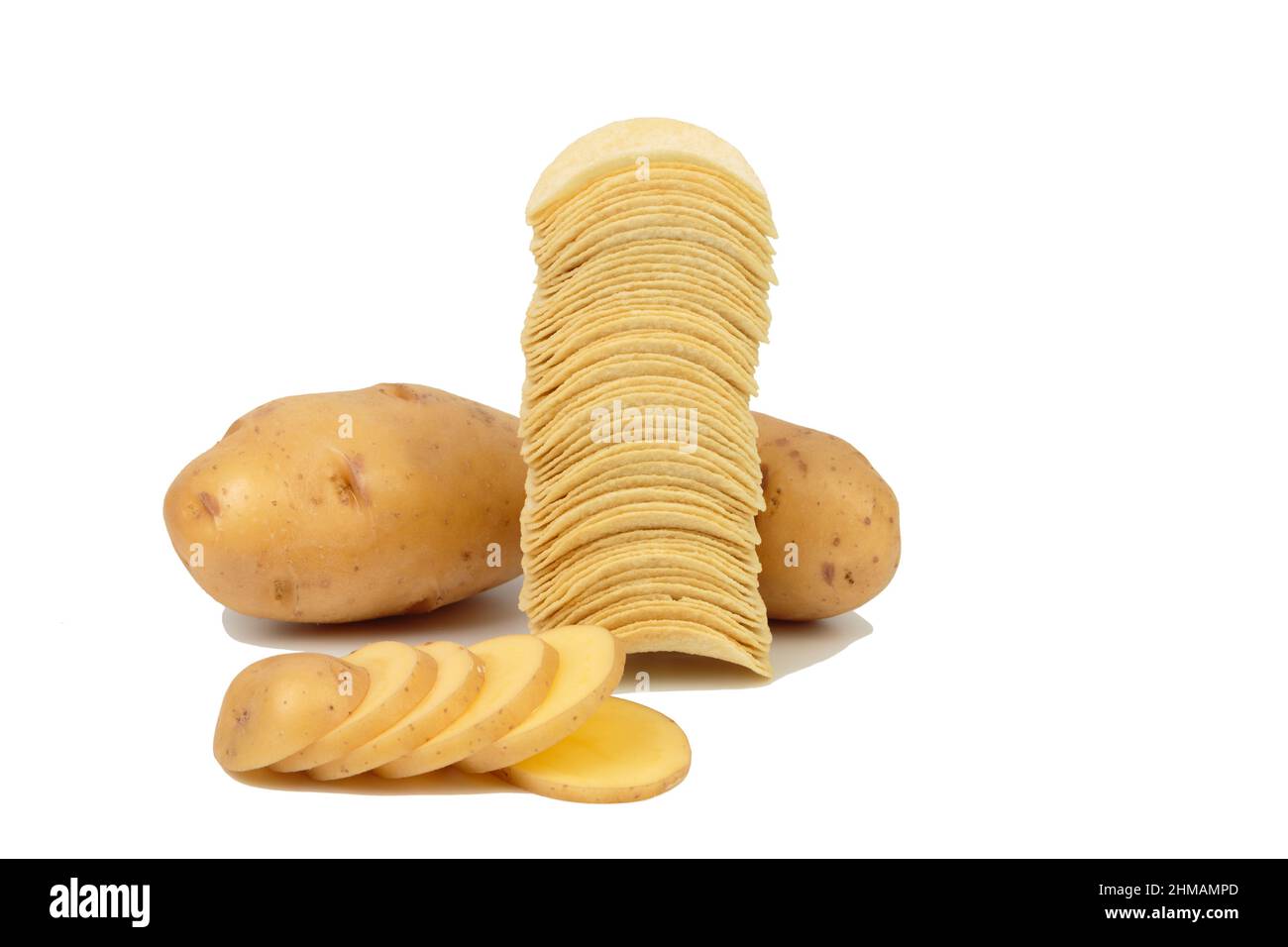 Pommes de terre crues et une pile de chips. Isolé sur le mérou blanc. Gros plan. Banque D'Images