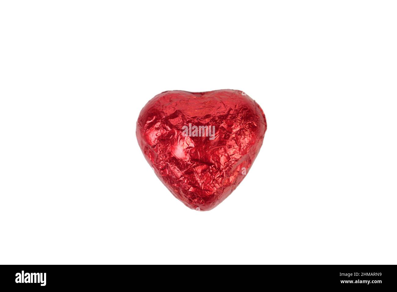 Bonbons au chocolat en forme de coeur enveloppés de papier d'aluminium rouge. Isolé sur fond blanc. Gros plan. Banque D'Images