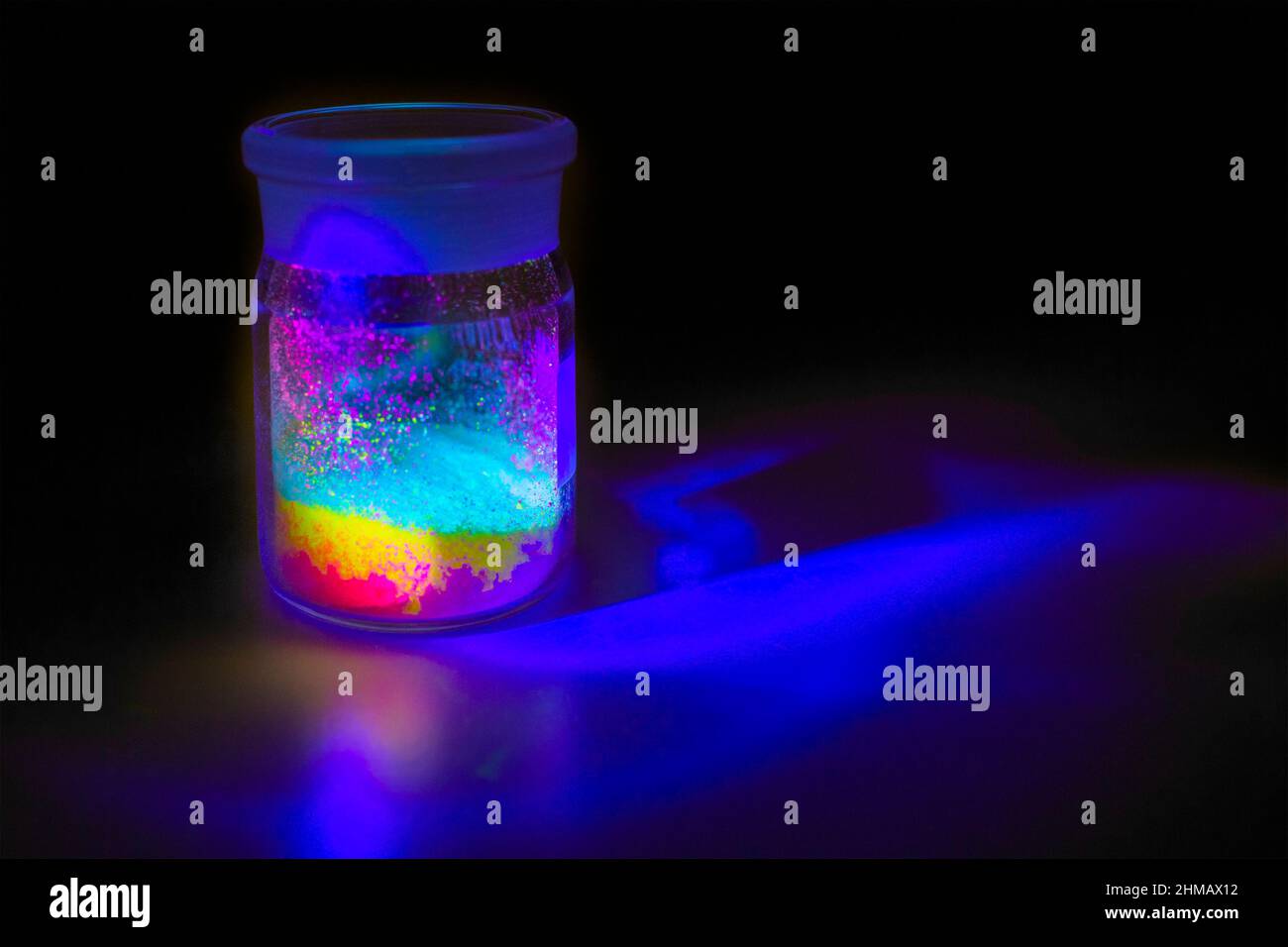 Matériaux organiques fluorescents comme une poudre de couleur rouge, jaune et verte pour la production d'OLED à l'intérieur des bouteilles en verre dans la lumière UV. Banque D'Images