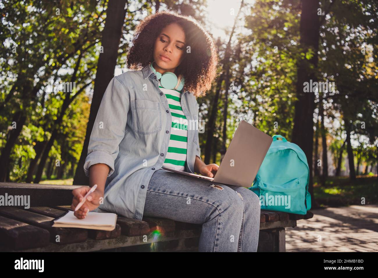 Photo de la jeune fille africaine intelligente attrayante écrire à la liste de faire distance enseignement organiser utiliser ordinateur portable à l'extérieur Banque D'Images