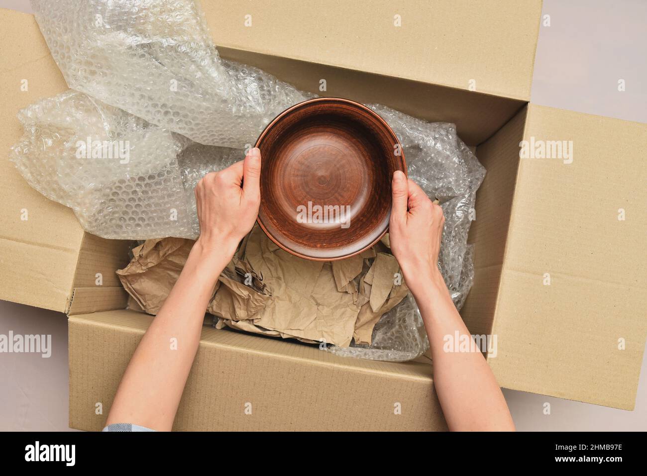 Femme empile la vaisselle dans une boîte avec papier d'emballage et vue de  film par le dessus. Déménagement dans une nouvelle maison. Déballage des  marchandises Photo Stock - Alamy