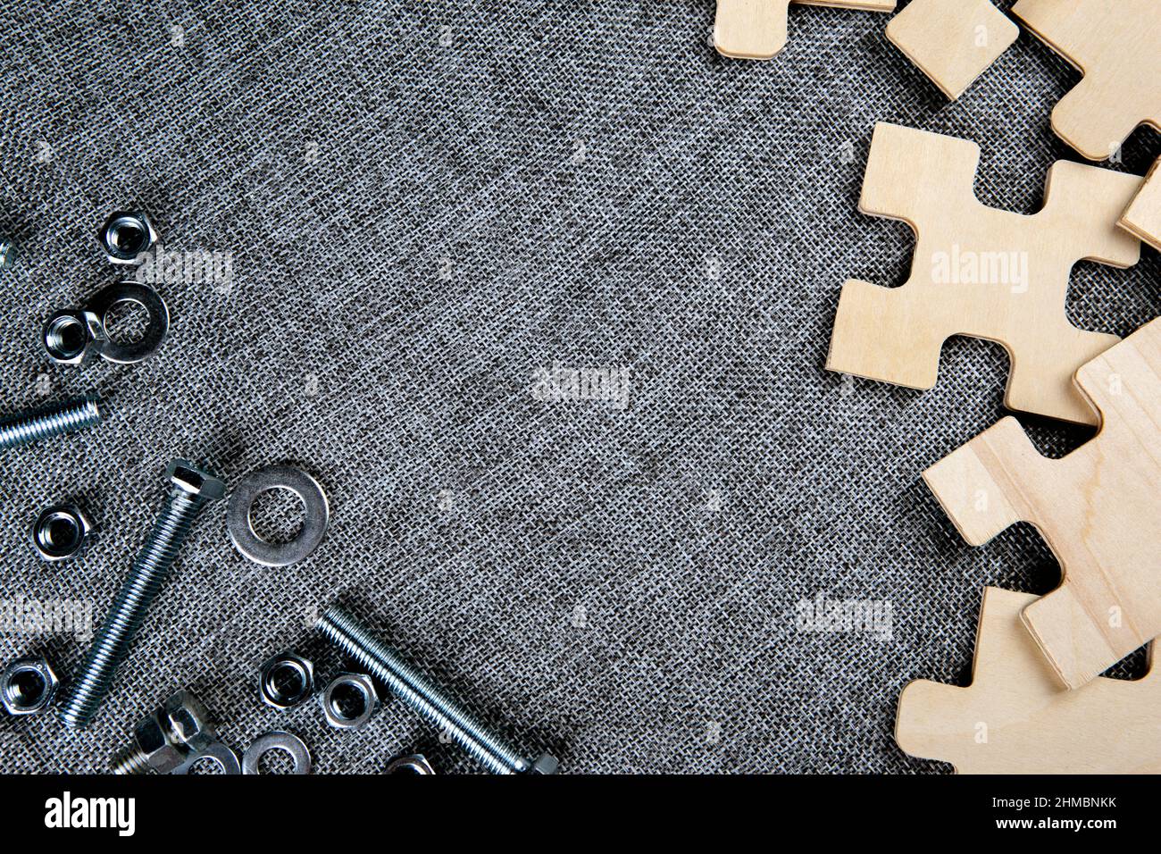 éléments de puzzle et écrous en acier, boulons sur un arrière-plan textile vue de dessus Banque D'Images