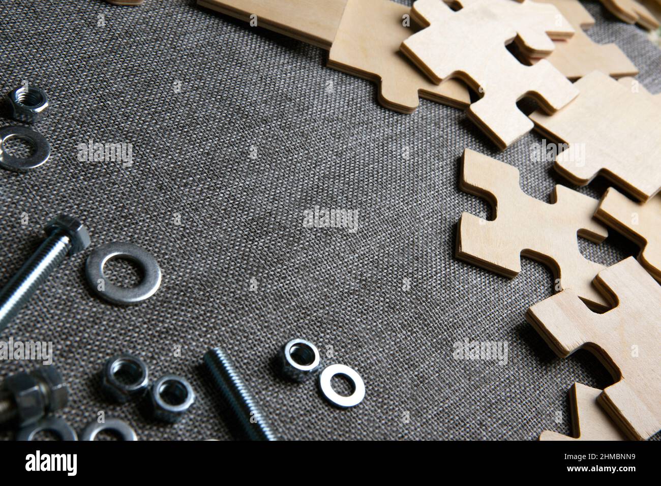 éléments de puzzle sur un fond textile et et écrous en acier, gros plan de boulons Banque D'Images