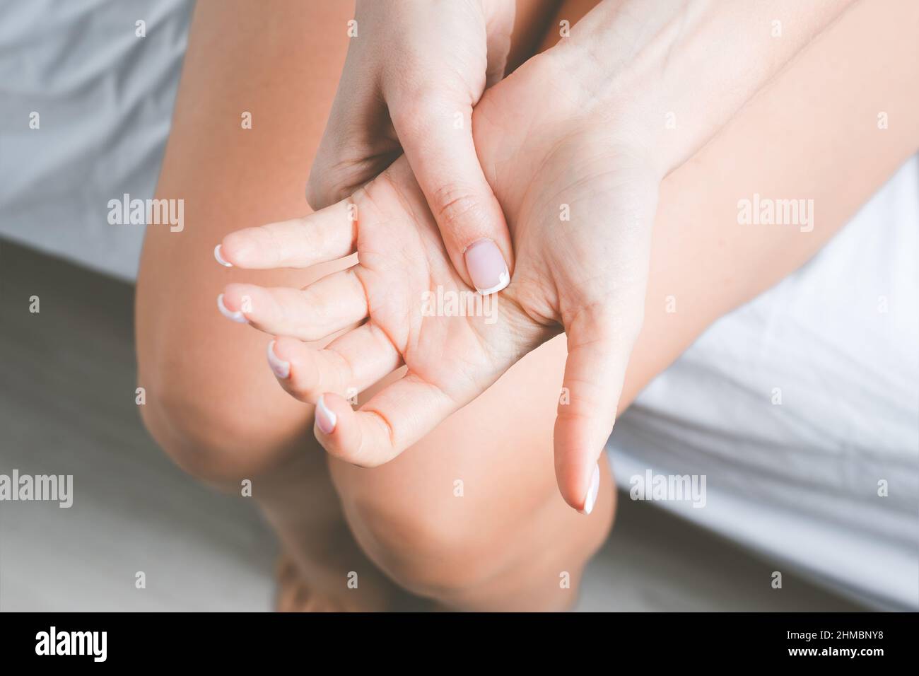 Femme souffrant de douleurs aux mains ou aux doigts. Engourdissement de la main ou engourdissement du membre après le sommeil. Masser la main douloureuse Banque D'Images