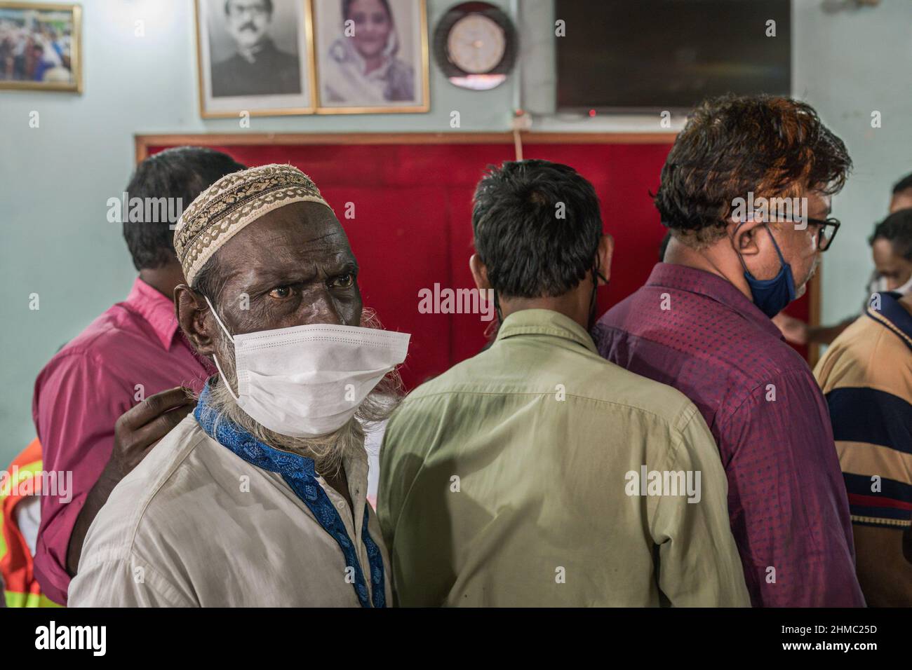 Un homme avec un masque de protection déchiré dans une file d'attente attendant de recevoir le vaccin de SARSCOV2 pendant la campagne de vaccination.a Dhaka, Bangladesh, la capitale du pays le plus densément peuplé du monde, la pandémie de COVID est une histoire chaotique depuis que les restrictions gouvernementales ont commencé à tenter de prévenir les infections et les décès. Dhaka est une mégapole croissante avec plus de 20 millions d'habitants au bruit et à la ruée quotidienne, mais sans les infrastructures nécessaires et avec plus de 60% de sa population travaillant de manière informelle et embourbée dans la pauvreté, le chaos s'est intensifié à tous les niveaux. Banque D'Images