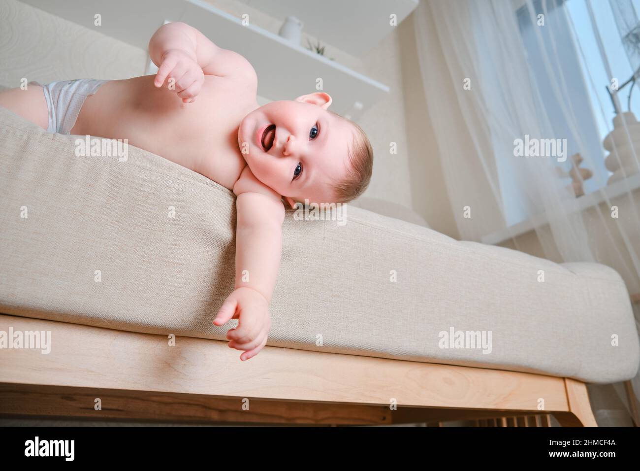 Bébé tombe du canapé dans le salon de la maison. Le tout-petit sort du lit.  Problèmes avec la sécurité des enfants sans surveillance parentale Photo  Stock - Alamy