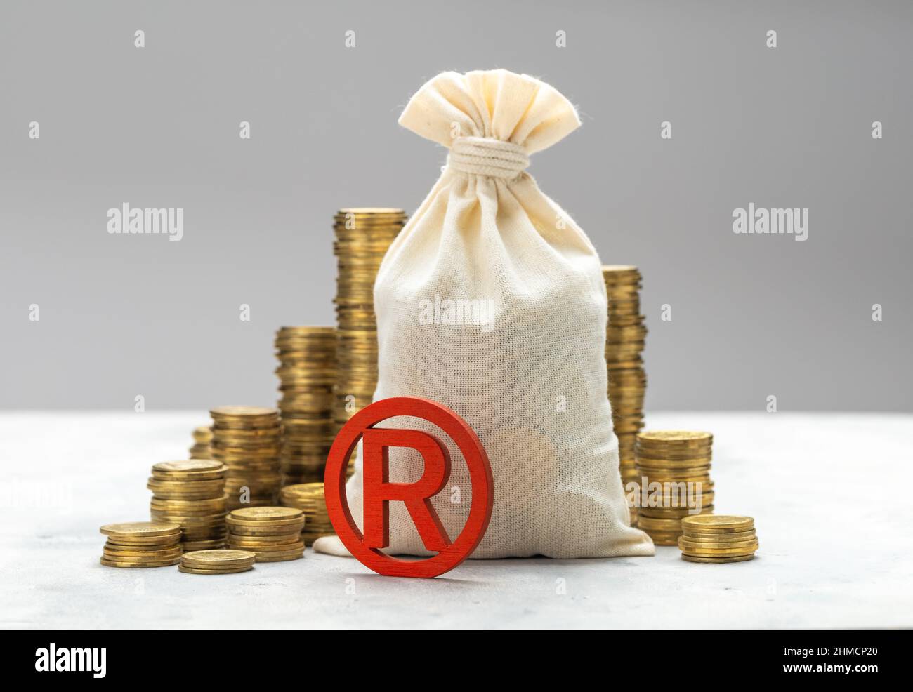 Marque déposée et sac d'argent avec pièces d'or sur fond gris. Banque D'Images
