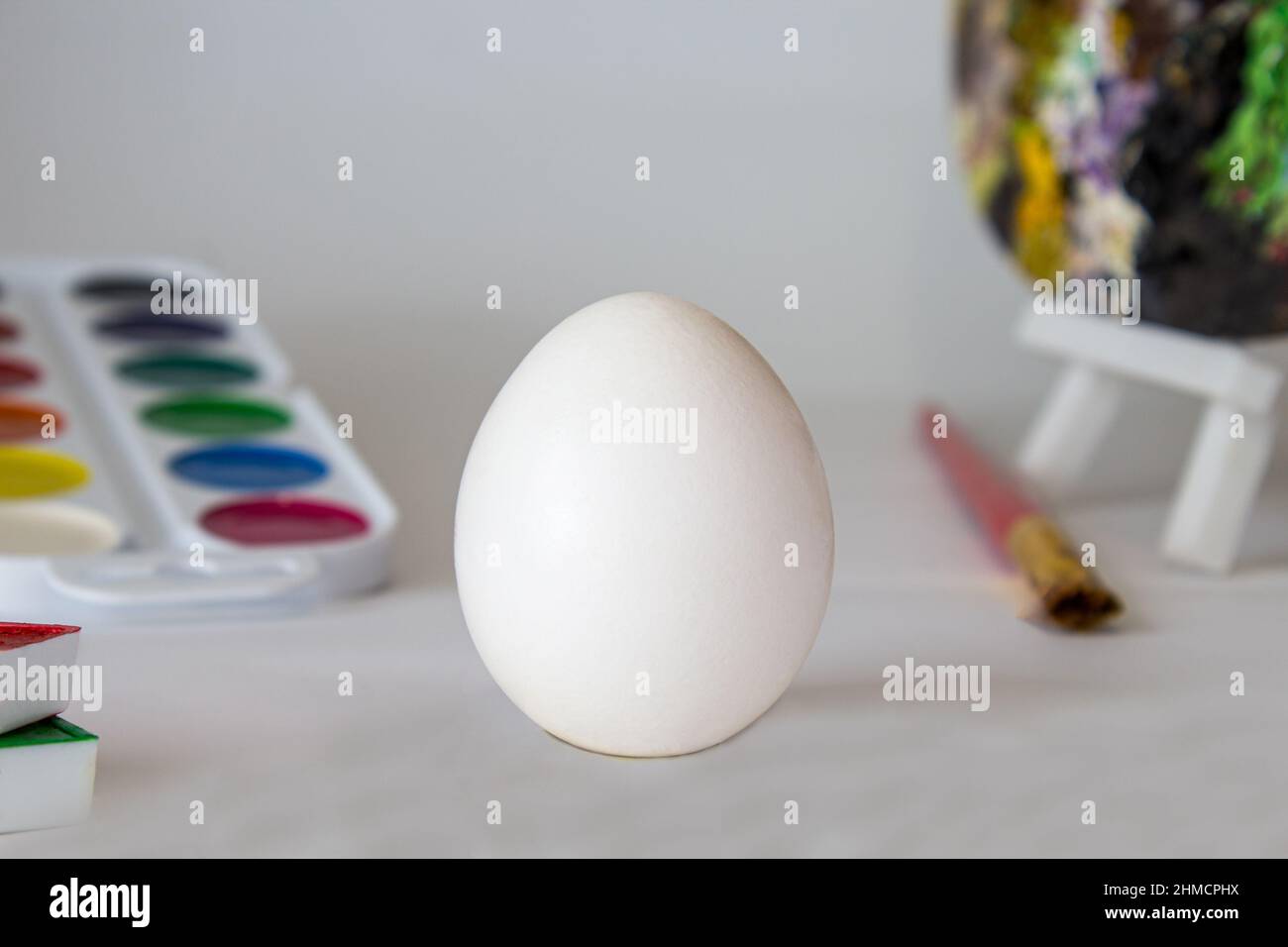 Œuf de Pâques blanc sur fond aquarelle. Composition de vacances simple. Symbolisme du concept du festival des oeufs de Pâques. Travail d'art, fait main, créativité Banque D'Images