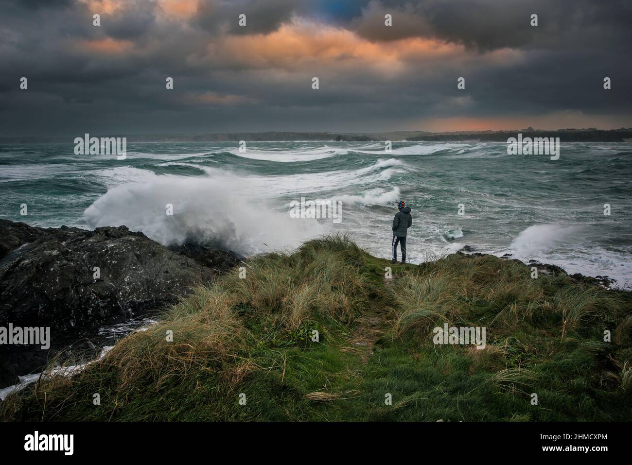 Une personne debout sur Towan Head qui observe le temps sauvage et les mers sauvages dans la baie de Newquay causés par la tempête Arwen dans les Cornouailles. Banque D'Images