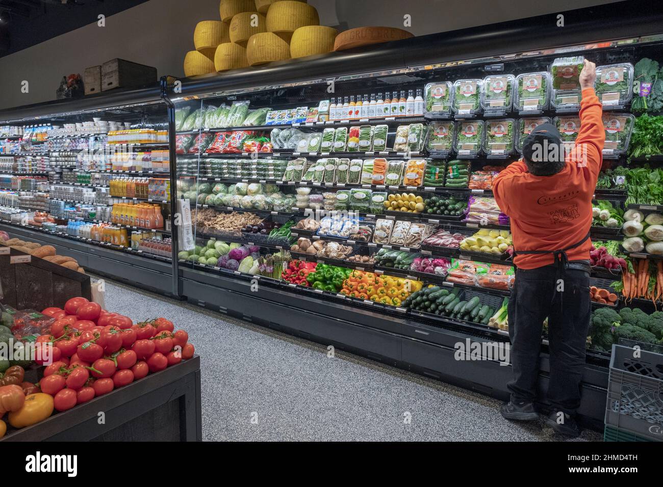Un ouvrier réapprovisionnez les étagères de la section des légumes de Citarella's, un supermarché haut de gamme situé au 6th Avenue à Greenwich Village, New York. Banque D'Images