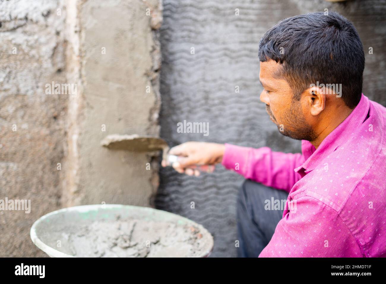 Pari quotidien indien occupé sur le travail de plâtre mural côté construction avec des gants de sécurité - concept de travail dur, concentré et de la construction. Banque D'Images