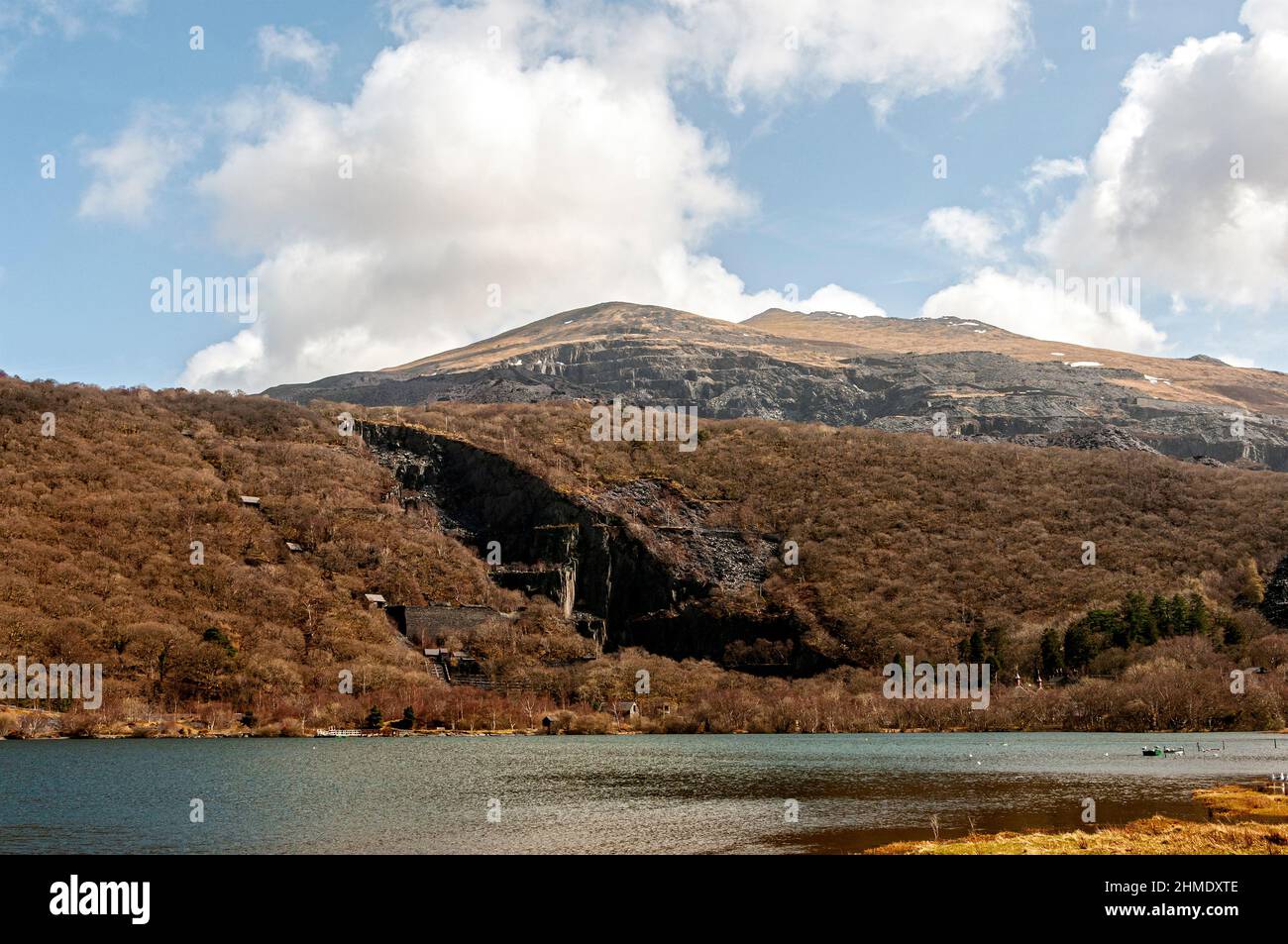 La cicatrice à plusieurs niveaux gris exposée de marches géantes en chute libre et de bâtiments restants de mines d'ardoise abandonnées mar les pentes enneigées d'une montagne accidentée Banque D'Images