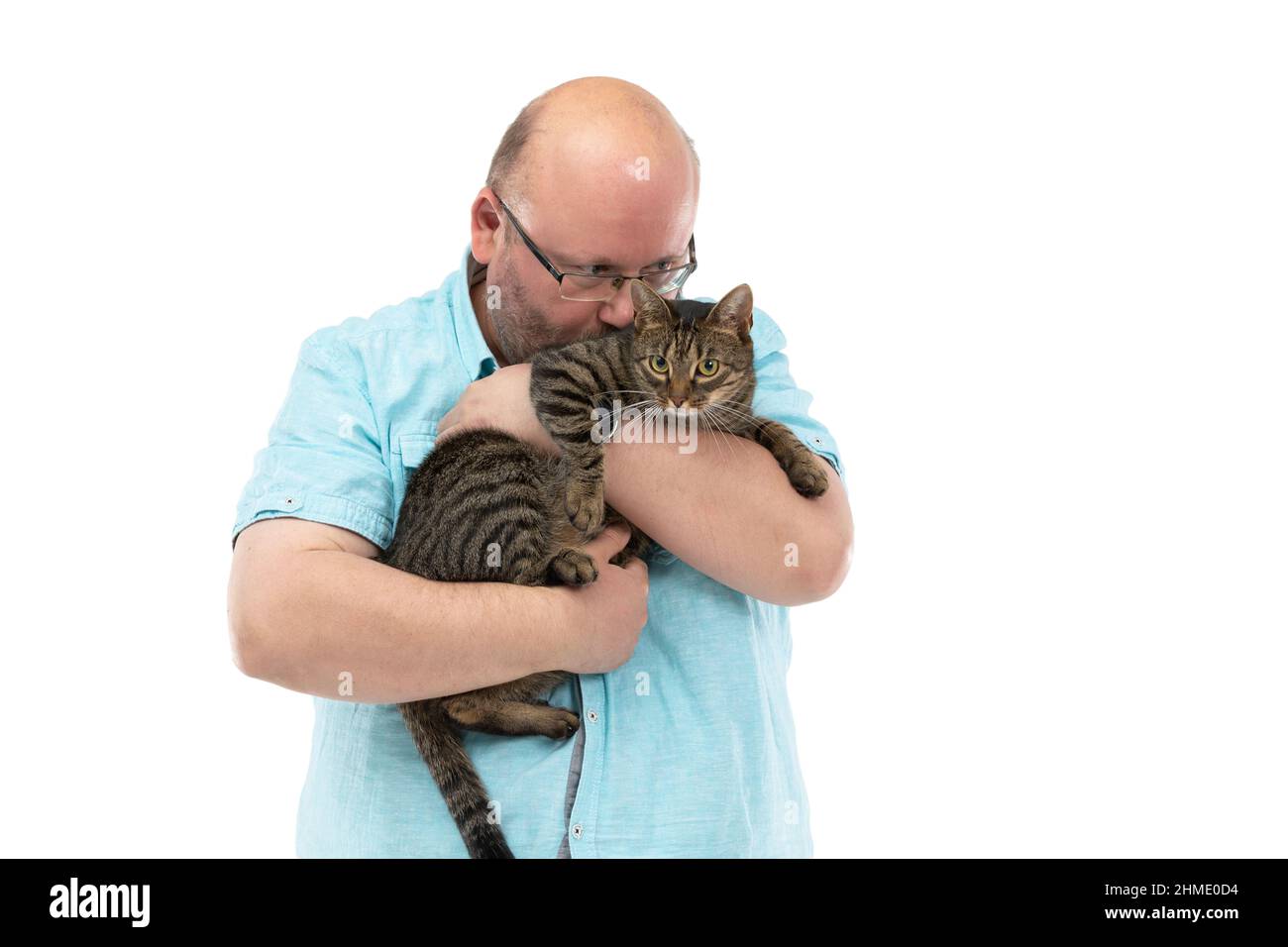 Un homme chauve tient un chat-elle dans ses bras et l'embrasse. Banque D'Images