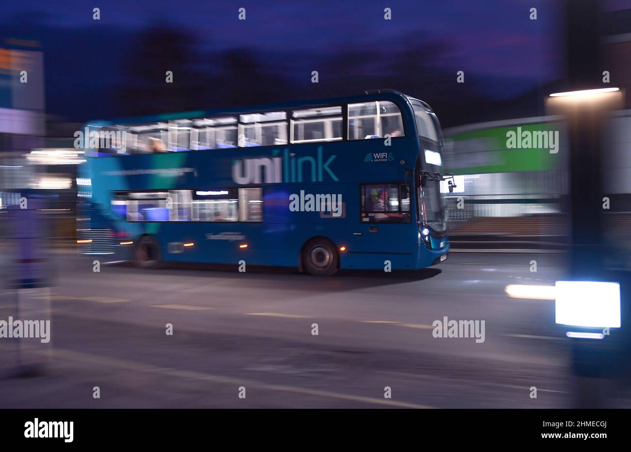Un bus bleu à impériale à liaison déliée, conduit pendant une prise de vue de nuit avec technique panoramique à Southampton, au Royaume-Uni, avec des passagers à bord avec espace de copie. Banque D'Images
