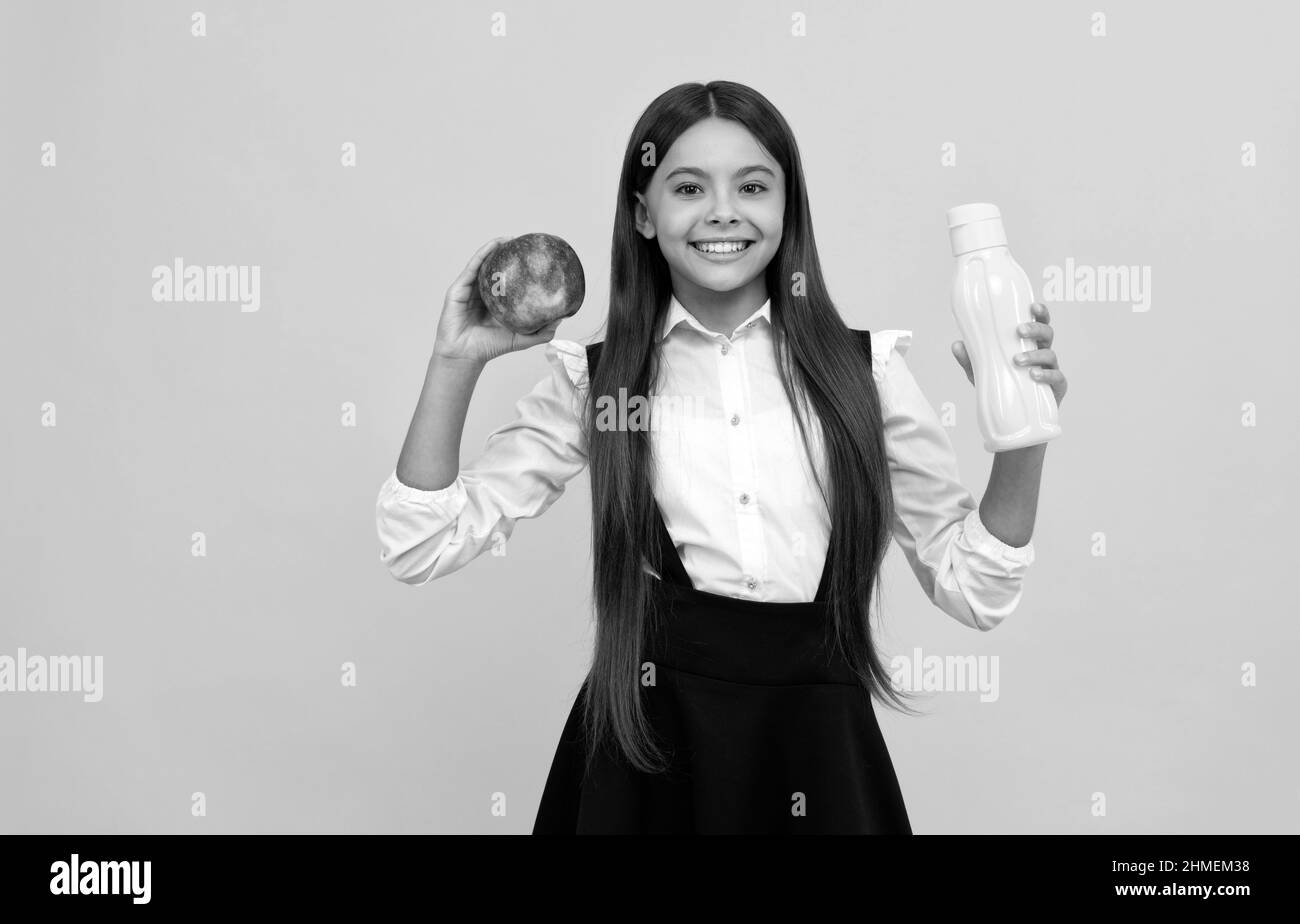 bonne école adolescente fille en uniforme tenir pomme et bouteille d'eau, santé Banque D'Images