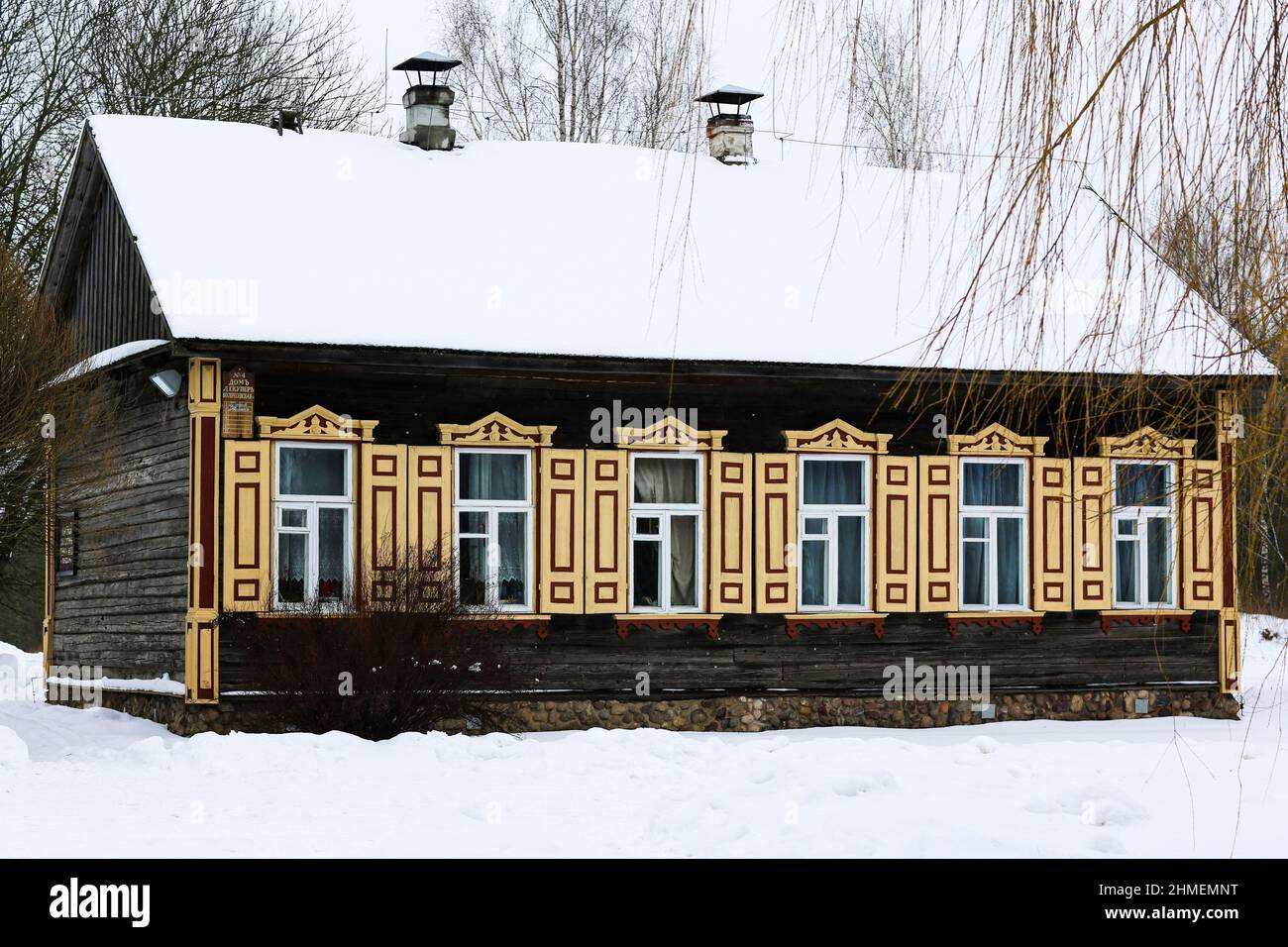 Ancienne maison en bois en rondins gris. Avec de belles fenêtres jaunes et des volets. Banque D'Images