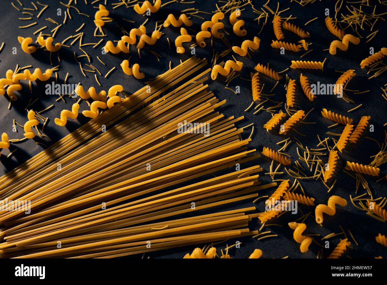 Motif avec différents types de pâtes et spaghetti sur fond noir. Concept de cuisine italienne. Banque D'Images