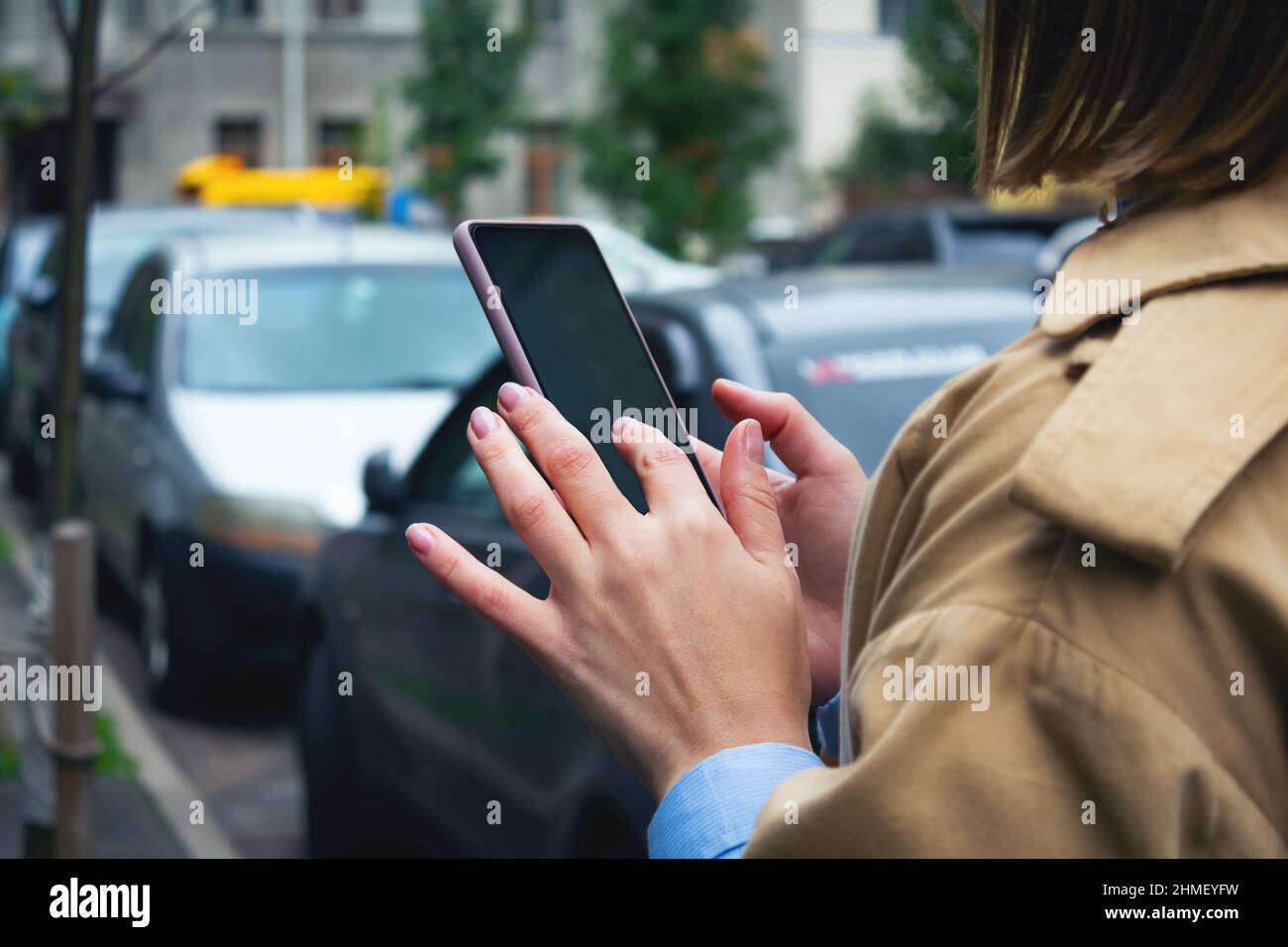Femme tenant le téléphone portable entre les mains.Partage de voitures. Banque D'Images