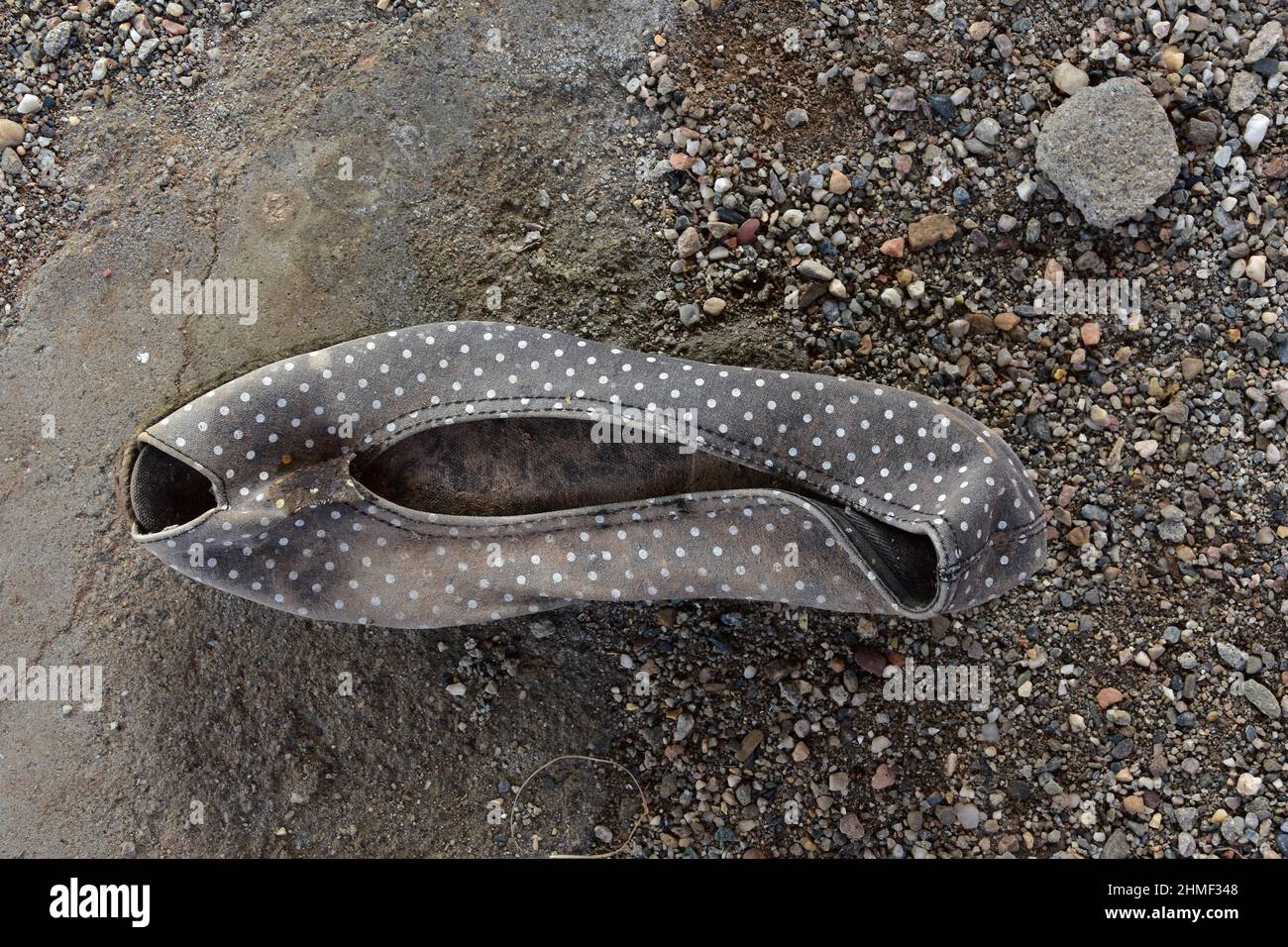 Chaussure pour femme à pois noir et blanc sur le sol, chaussure en cuir délabré, chaussure pourrie, chaussure épave, chaussure usée, ancienne chaussure Banque D'Images