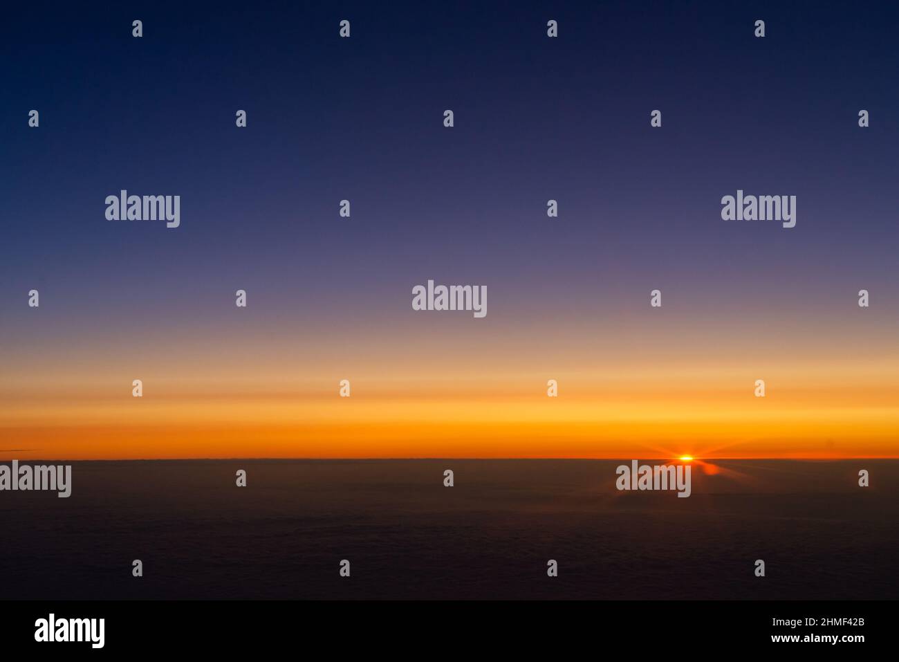 Lever de soleil depuis la fenêtre de l'avion. L'horizon est coloré par la lumière orange du soleil. Les premiers rayons du soleil levant. Banque D'Images